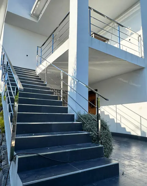 Escalera exterior con barandilla de acero inoxidable en una vivienda blanca