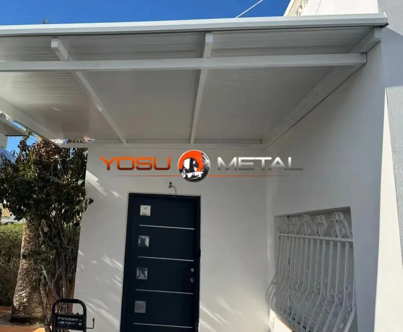 Porche metálico blanco sobre la puerta de entrada de una vivienda