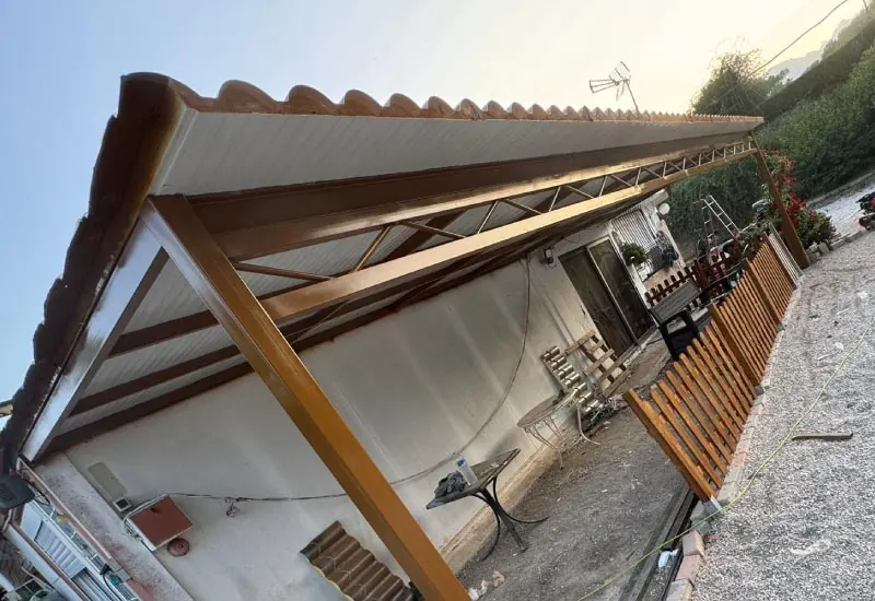 Porche metálico alargado junto a una vivienda