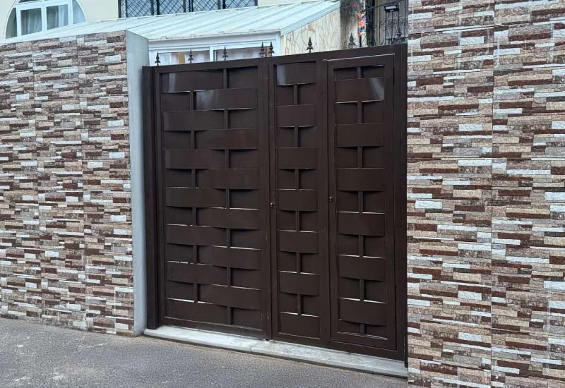 Portón metálico de dos hojas en color marrón con diseño trenzado