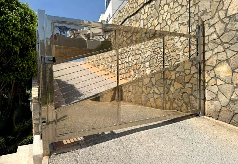Portón corredero de acero inoxidable con lamas horizontales en la entrada de una vivienda