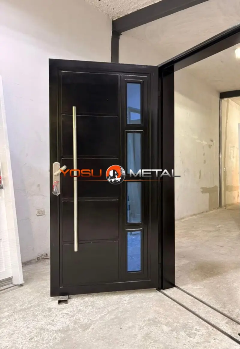 Puerta de entrada metálica negra con tirador de acero inoxidable y cuatro cristales verticales