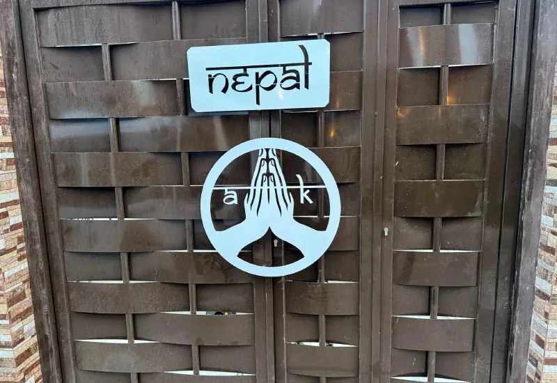 Puerta peatonal metálica con diseño trenzado y rótulo decorativo